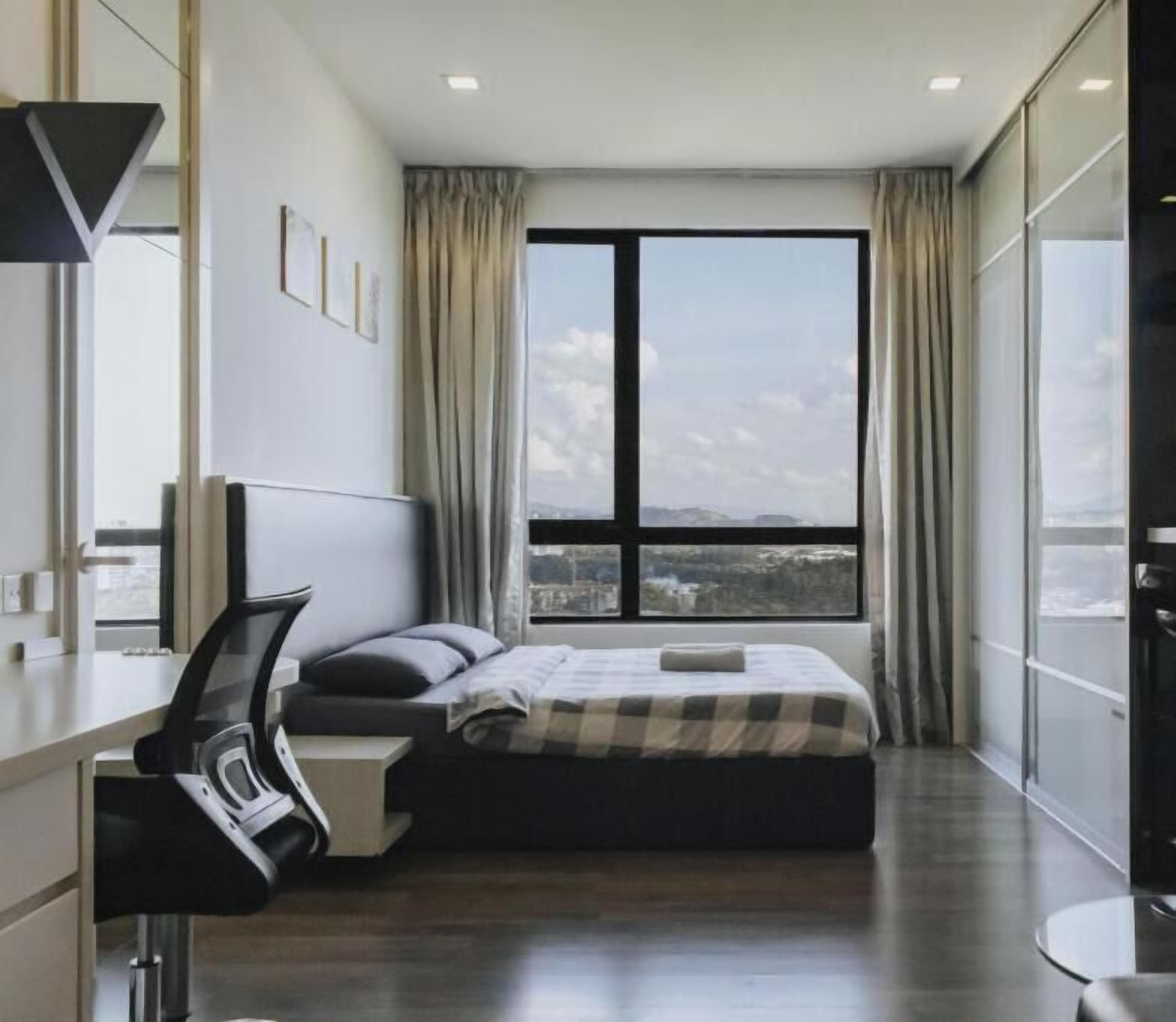 A modern hotel room with a large window, a bed, a desk, and a chair.