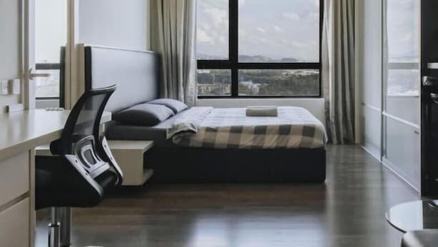 Ein modernes Hotelzimmer mit großem Fenster, einem Bett, einem Schreibtisch und einem Sessel.