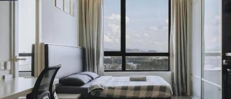 A modern hotel room with a large window, a bed, a desk, and a chair.