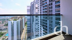 Um edifício residencial alto com várias varandas, grandes janelas e vista clara do horizonte urbano.