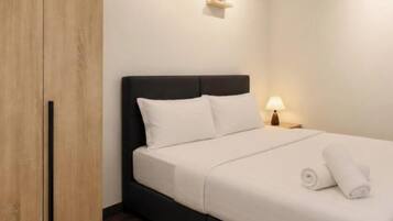 A bedroom with a bed, a wardrobe, a nightstand, and a wall-mounted shelf.