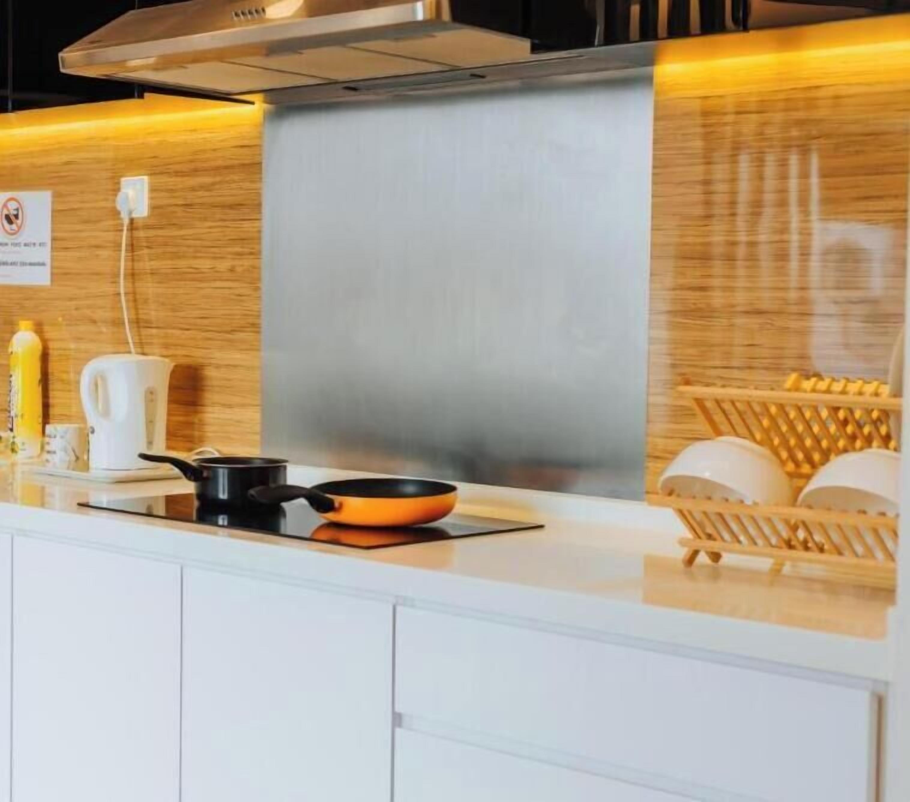 A modern kitchen with a stainless steel range hood, a white countertop, and a wooden backsplash.