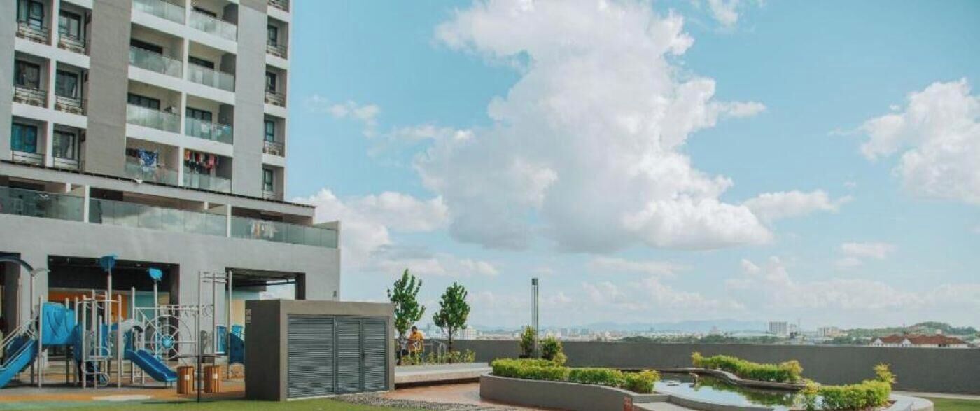 A modern building with a playground, a water feature, and a clear view of the city skyline.