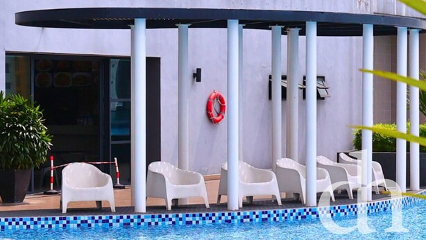 Une piscine avec des chaises blanches et une bouée de sauvetage accrochée au mur.