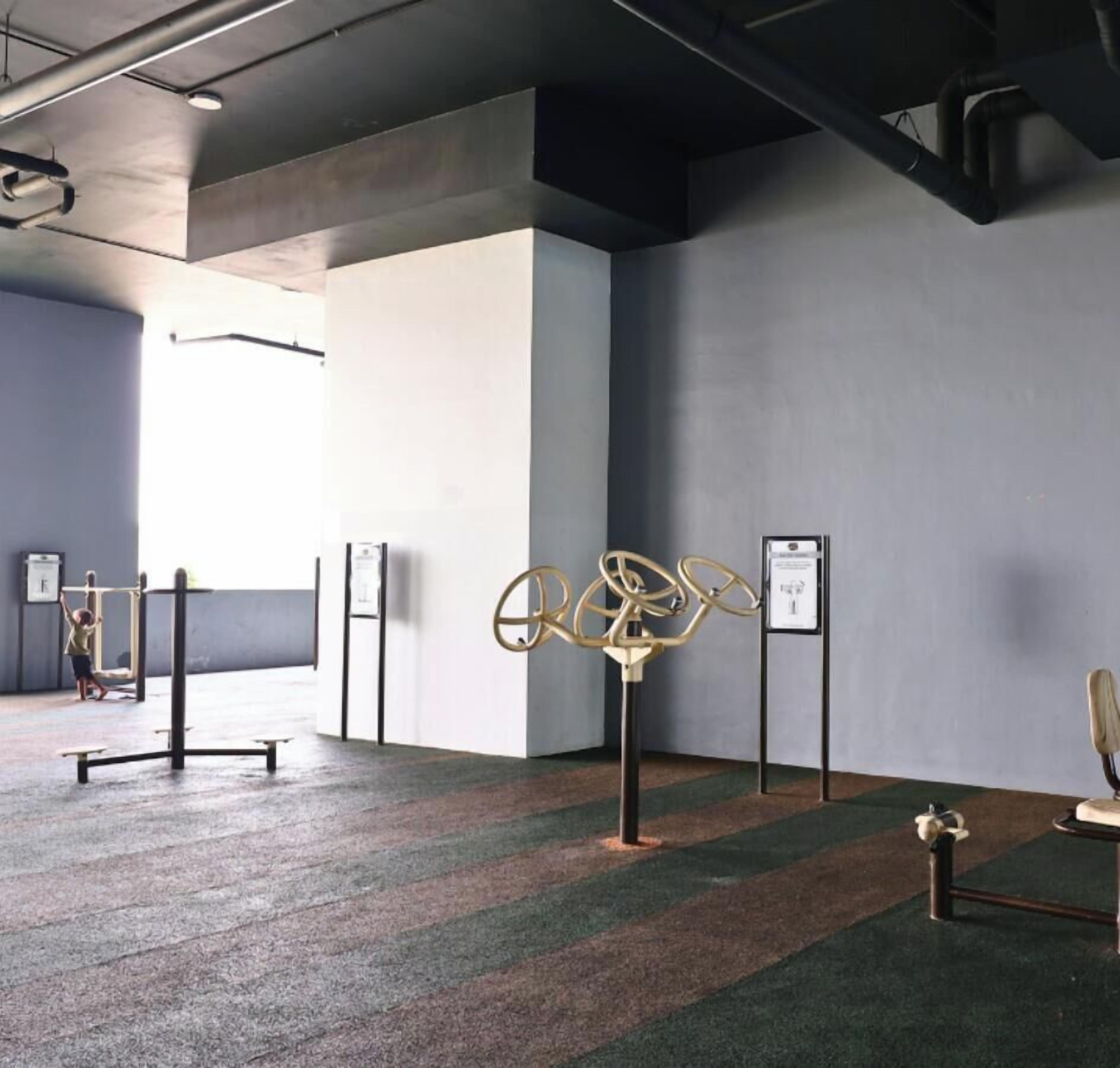 An indoor space with a grey floor, a metal sculpture, and a wall-mounted sign.