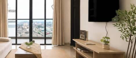 A modern living room with a large window, a flat-screen TV, a sofa, a coffee table, and a potted plant.