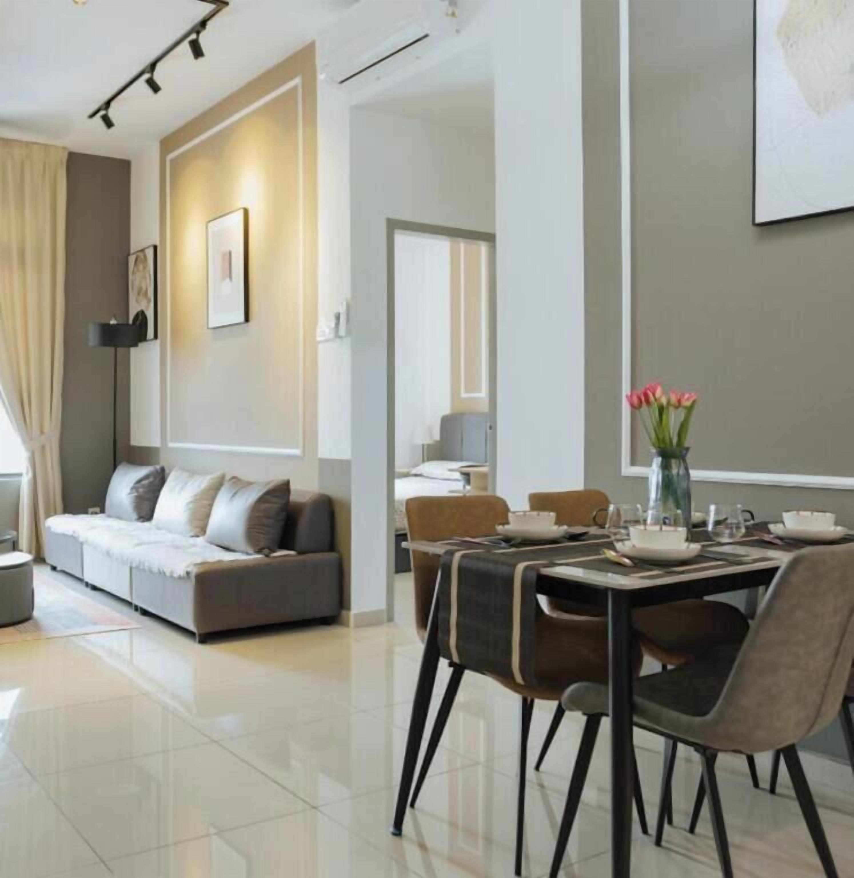 A modern dining area with a table set for four, a sofa, and a vase of flowers.