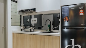 Una cocina moderna con armarios blancos, un refrigerador negro y una campana de acero inoxidable.