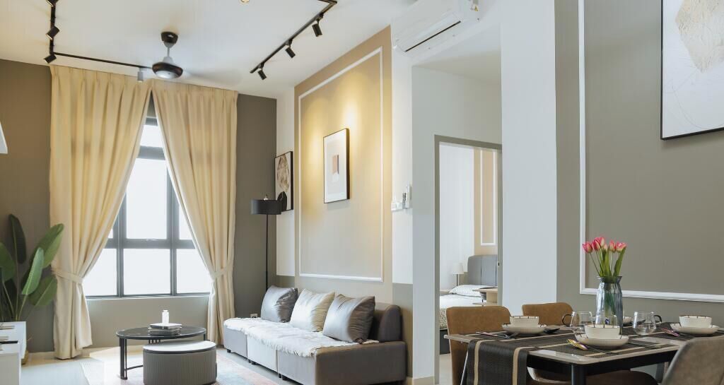 A modern living room with a sofa, a dining table set, and a large window with curtains.