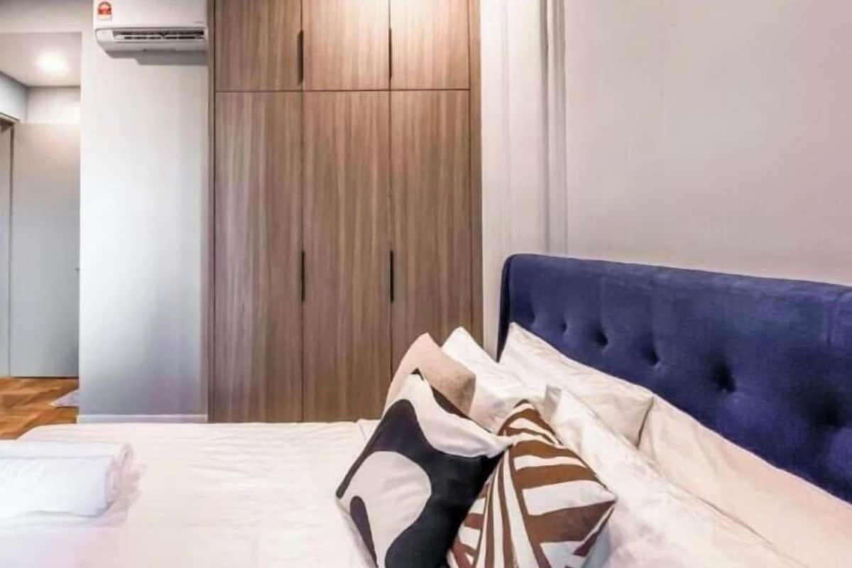 A bedroom with a bed, a wardrobe, and an air conditioning unit.