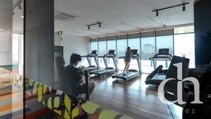 Academia com esteiras, uma pessoa usando bicicleta ergométrica e uma criança em uma esteira.