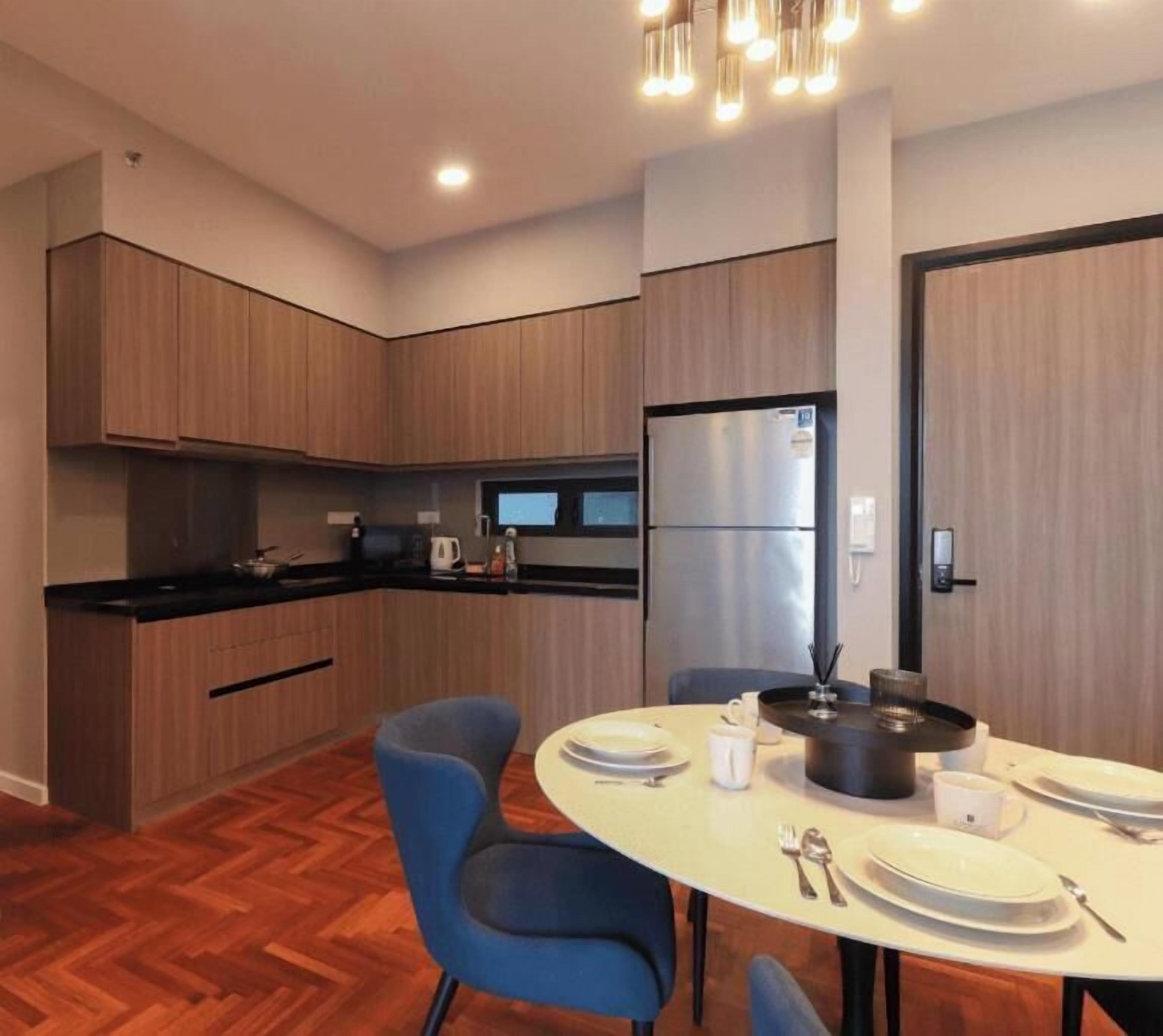 A modern kitchen with wooden cabinets, a black countertop, and a dining area with a round table and blue chairs.