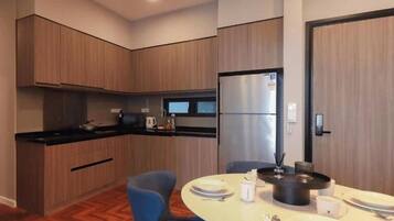 A modern kitchen with wooden cabinets, a black countertop, and a dining area with a round table and blue chairs.