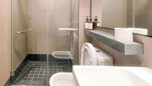 A modern bathroom with a glass-enclosed shower, a toilet, and a sink with a marble countertop. - Bloomsvale Residence OKR By Dehoz Suites (Kuala Lumpur)