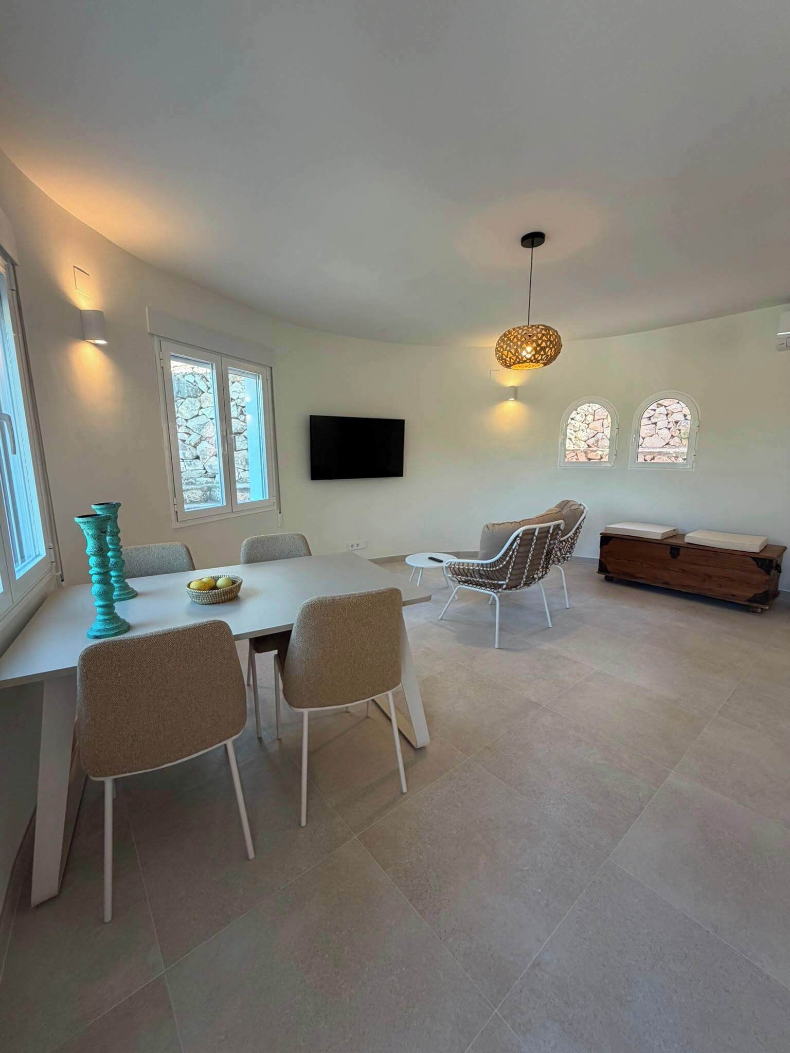 A modern dining area with a white table, beige chairs, and a decorative teal vase.
