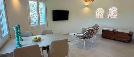 A modern dining area with a white table, beige chairs, and a decorative teal vase.