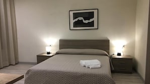 A neatly made bed with a herringbone-patterned bedspread and two bedside lamps.