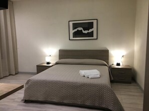 A neatly made bed with a herringbone-patterned bedspread and two bedside lamps.