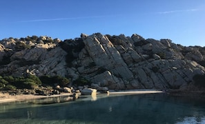 A rocky coastline with clear water and a beach.