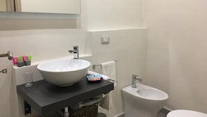 A bathroom with a white sink, a mirror, and a white toilet.