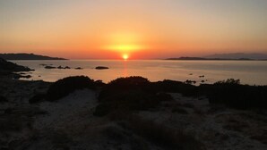 A sunset over a calm body of water with land on the horizon.