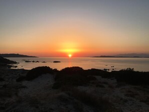 A sunset over a calm body of water with land on the horizon.