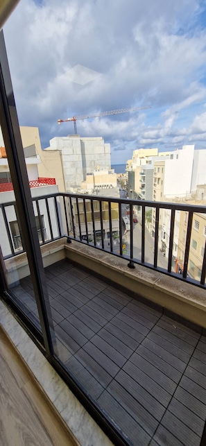 Ein Balkon mit Blick auf eine Stadtlandschaft, einschließlich Gebäude und eines Kräns.