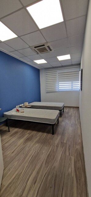 A room with a blue accent wall, a large window with blinds, and a ceiling with square light fixtures. - Enjoy Sliema from this spacious 2-bedroom, 2-bathroom apartment with a private balcony and sea glimpse. With a comfortable living area, equipped kitchen and washing machine, it is ideal for families, couples and longer Malta stays. (Tas-Sliema)