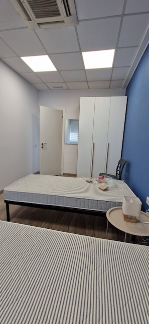 Ein Zimmer mit einem Bett, einem Schreibtisch, einem Stuhl und einem Kleiderschrank.