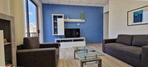 A modern living room with a TV, sofa, and coffee table. - Enjoy Sliema from this spacious 2-bedroom, 2-bathroom apartment with a private balcony and sea glimpse. With a comfortable living area, equipped kitchen and washing machine, it is ideal for families, couples and longer Malta stays. (Tas-Sliema)