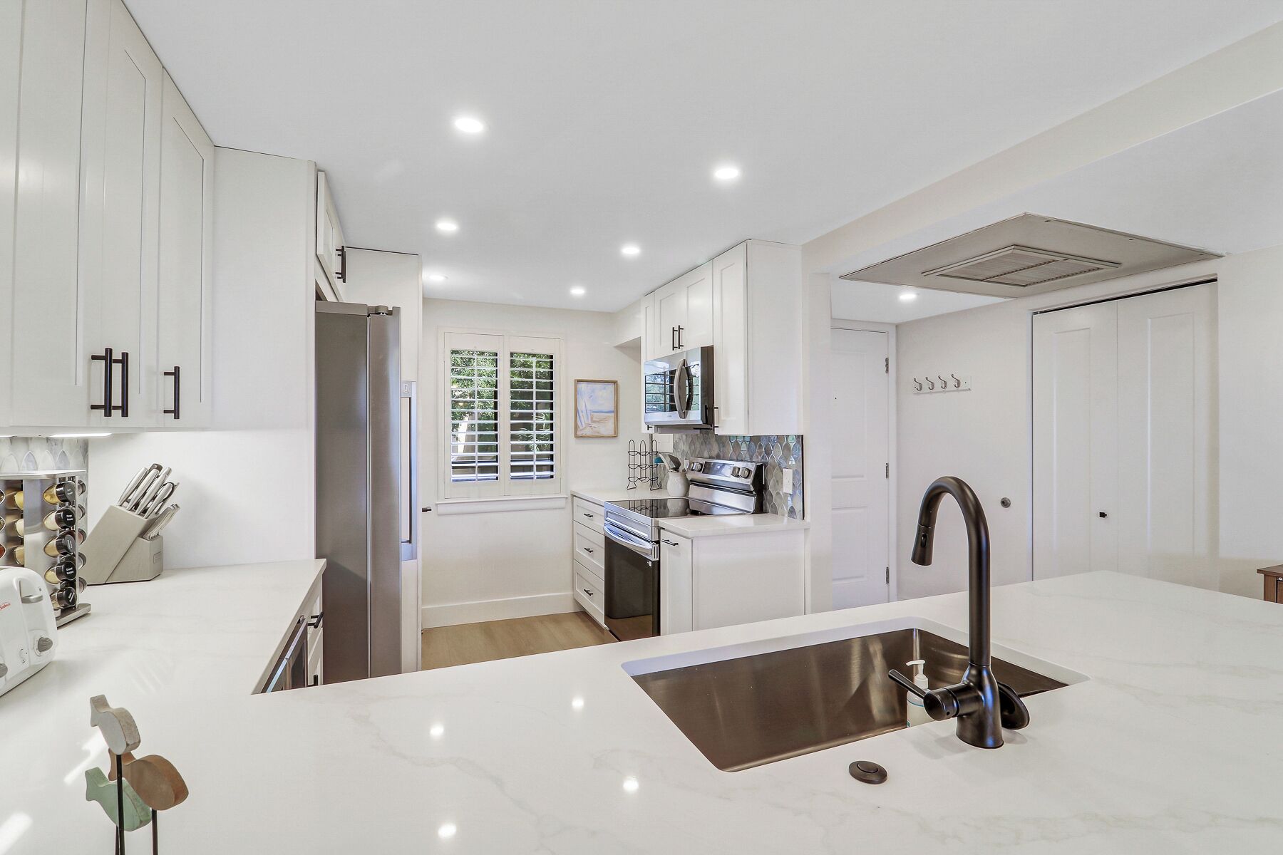 A modern kitchen with white cabinetry, a stainless steel sink, and a built-in oven.