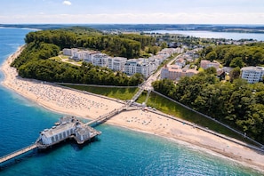 An aerial view of a coastal area with a beach, a pier, and residential buildings. - Villa Manatee - Wellness Apartment with a Balcony (Sellin)