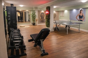 A gym with exercise equipment, a ping pong table, and a mural. - Villa Manatee - Wellness Apartment with a Balcony (Sellin)
