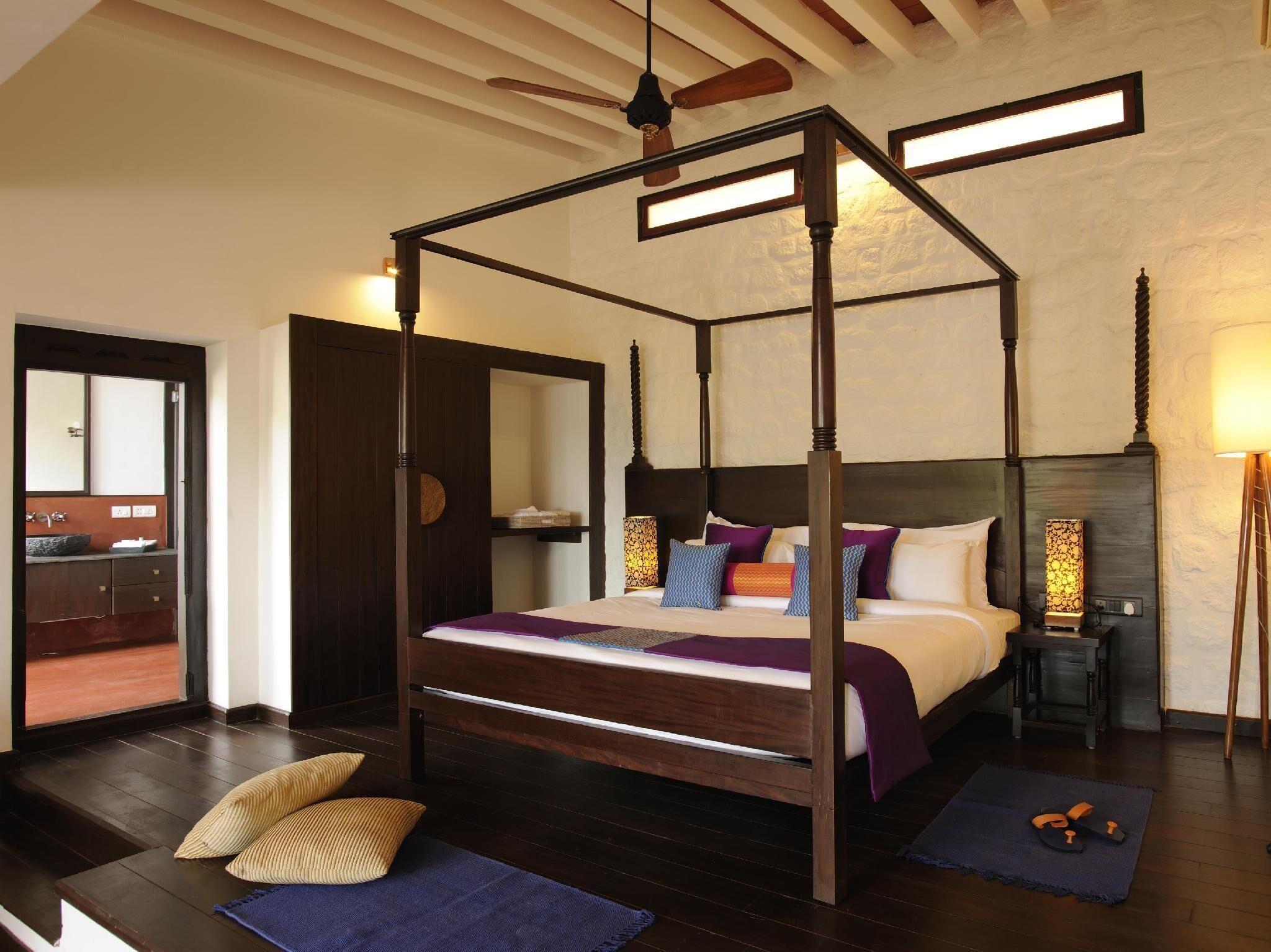 A four-poster bed with a wooden frame, a headboard, and a bedside table with a lamp.