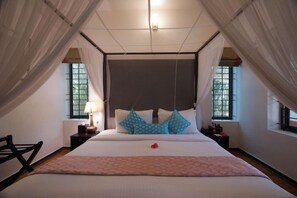 A bedroom with a large bed, two bedside tables with lamps, and a window with curtains. - Niraamaya Retreats Surya Samudra Kovalam (Neyyattinkara)