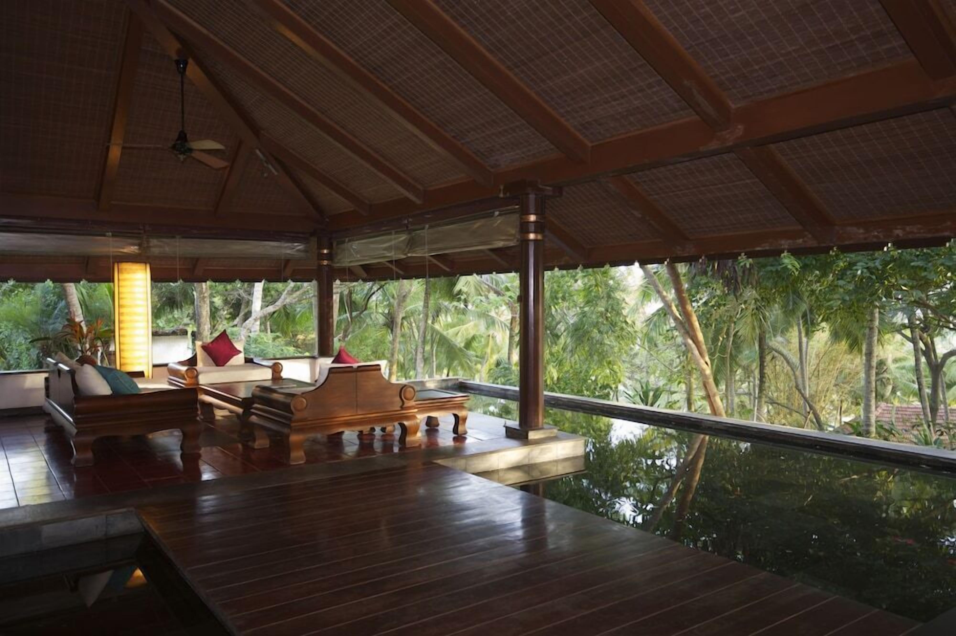 A room with a wooden floor, a sofa, a table, and a view of the outdoors.