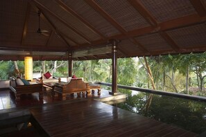 Ein Zimmer mit Holzboden, einer Couch, einem Tisch und Blick ins Freie.