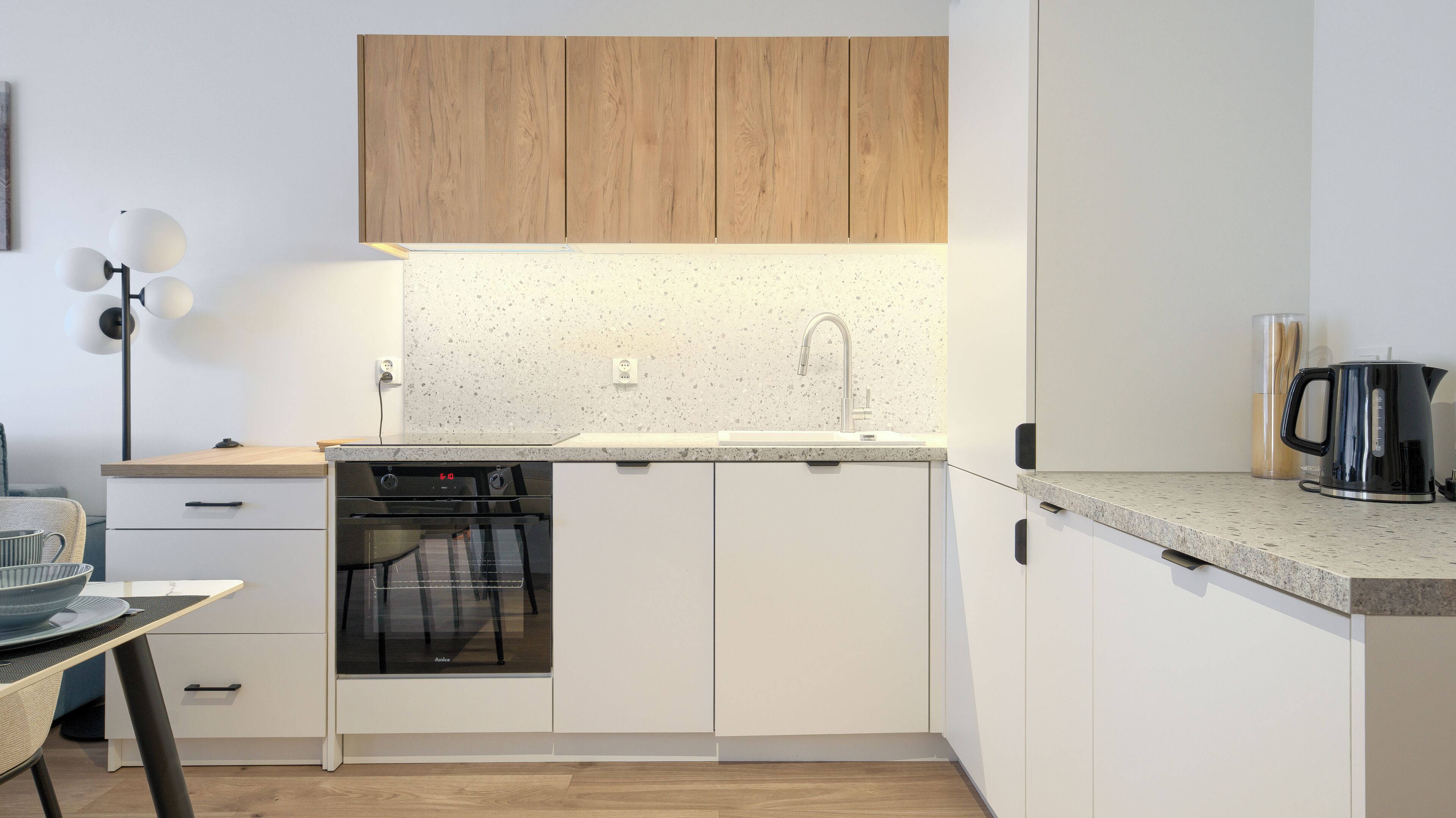 A modern kitchen with a dishwasher, oven, and a coffee maker on the countertop.