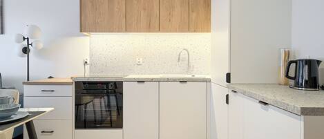 A modern kitchen with a dishwasher, oven, and a coffee maker on the countertop.