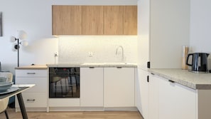 A modern kitchen with a dishwasher, oven, and a coffee maker on the countertop. - Apartamenty Sun & Snow Plażowa V (Międzywodzie)