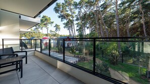 A balcony with a glass railing, a table, and chairs. - Apartamenty Sun & Snow Plażowa V (Międzywodzie)