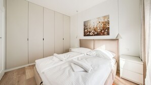 Een hotelkamer met een bed, nachtkastje, kledingkast en een schilderij aan de muur.