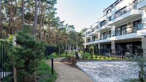 Een modern appartementencomplex met meerdere balkons, omringd door een bebost gebied.
