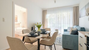A modern hotel room with a dining area, a sofa, and a view of the outdoors. - Apartamenty Sun & Snow Plażowa V (Międzywodzie)