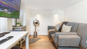 Ein modernes Wohnzimmer mit Fernseher, grauem Sofa, Couchtisch und einem Ringlicht.