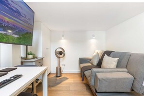 Ein modernes Wohnzimmer mit Fernseher, grauem Sofa, Couchtisch und einem Ringlicht.