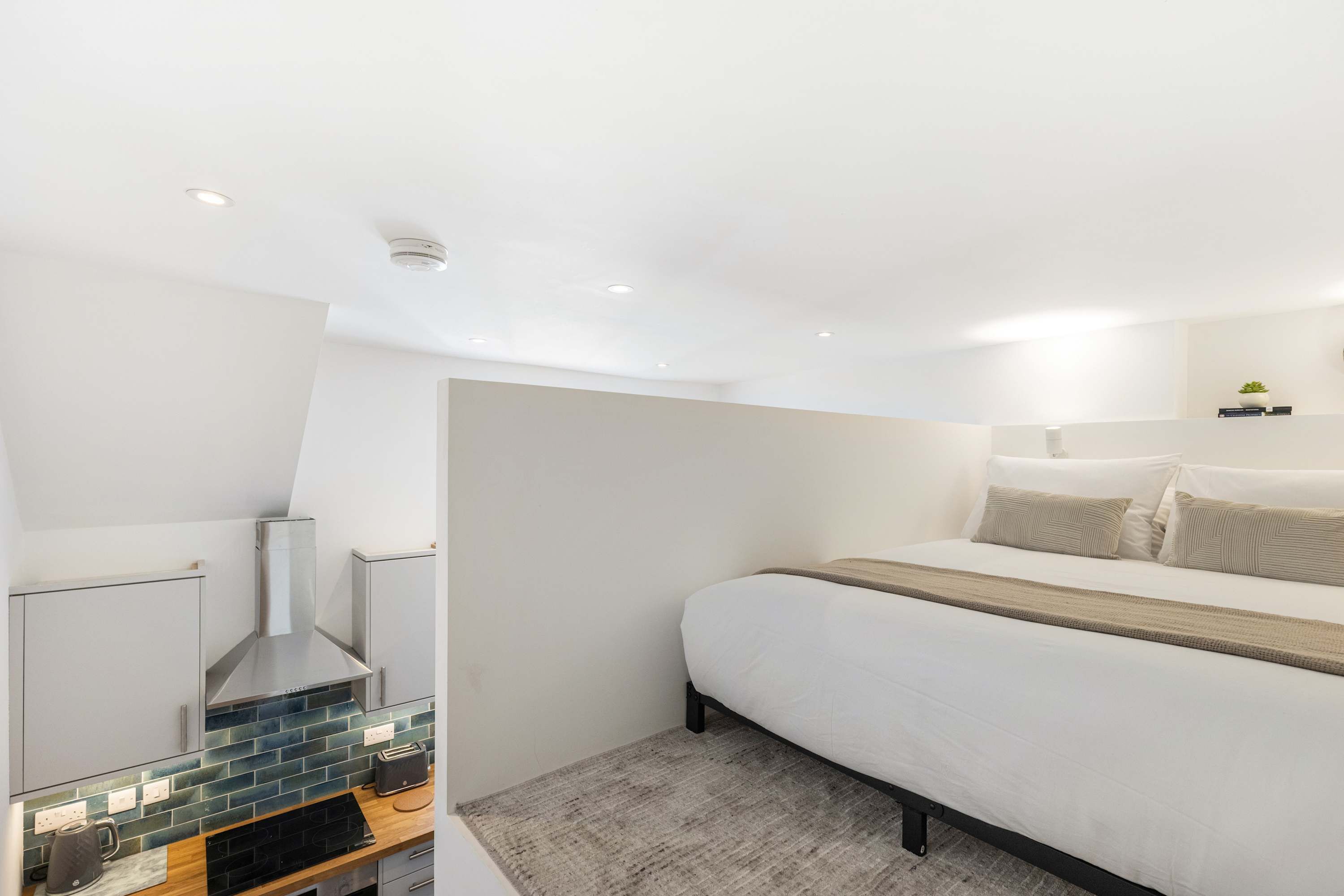 A modern bedroom with a bed, bedside table, and a built-in fireplace.