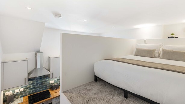 Ein modernes Schlafzimmer mit Bett, Nachttisch und integriertem Kamin.