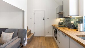 Eine kleine Küche mit einer Holzausziehtheke, einem eingebauten Backofen und einer gefliesten Spritzschutzwand.