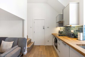 Eine kleine Küche mit einer Holzausziehtheke, einem eingebauten Backofen und einer gefliesten Spritzschutzwand.